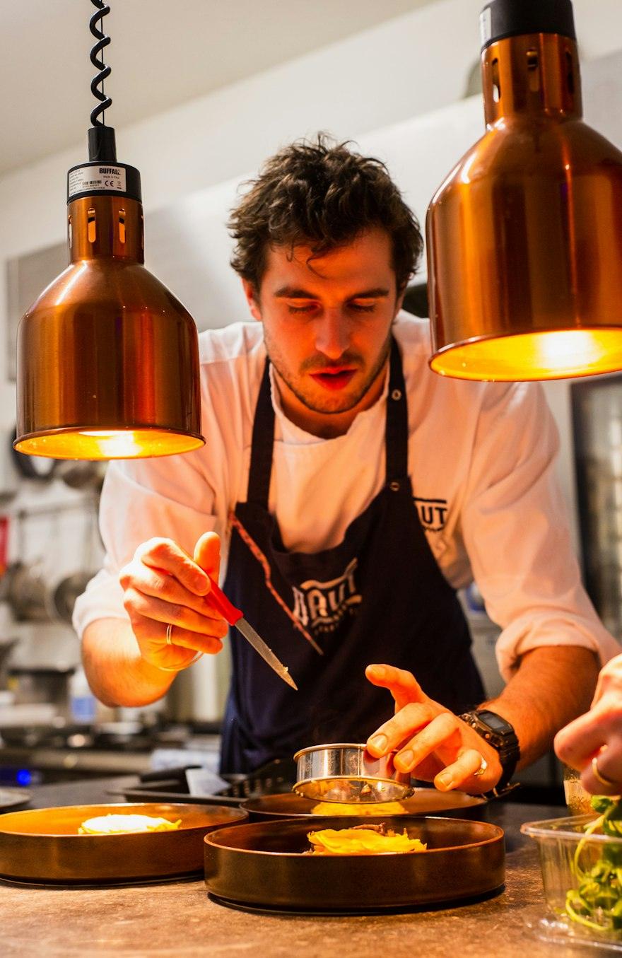 Cuiner amb davantal preparant un plat a la cuina