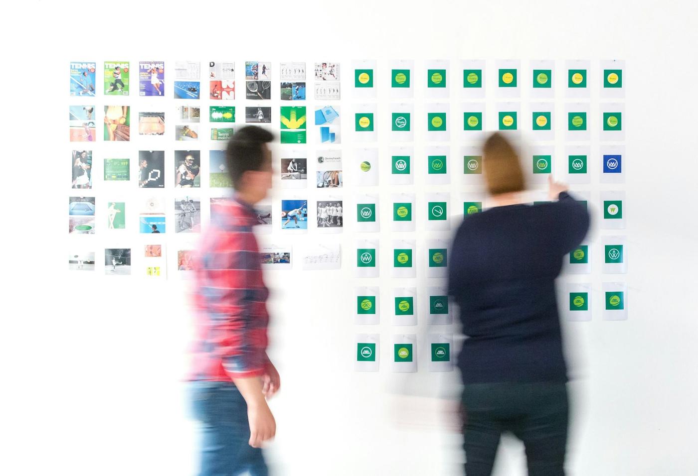 Dues persones de l’estudi revisant un mur d’imatges