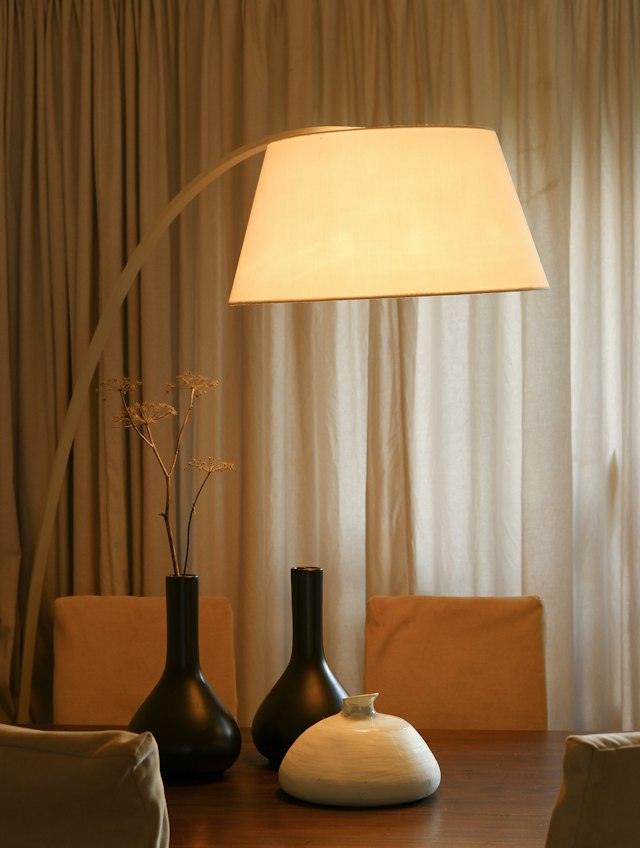 Llum de peu amb pantalla de tela encès en un menjador