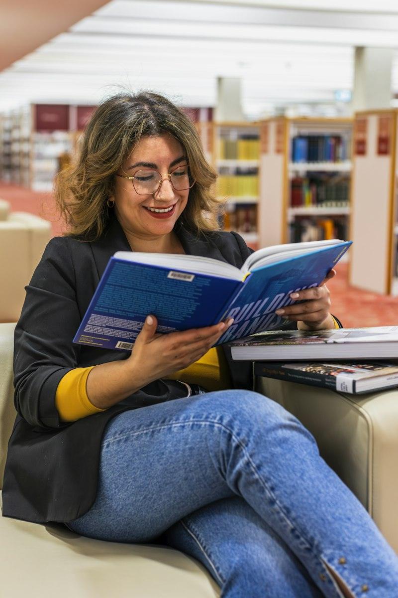 Dona llegint un llibre a la biblioteca
