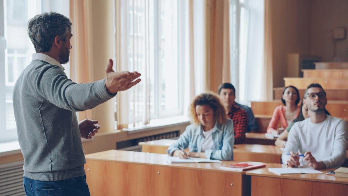 Professor explicant a un grup d’alumnes adults en una aula lluminosa