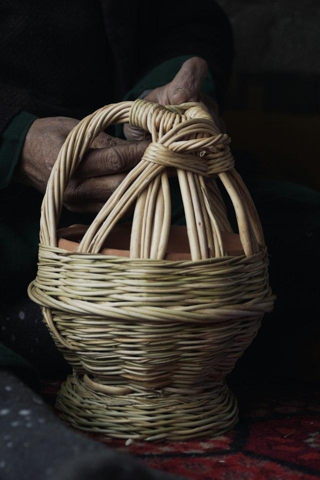 Mans d'un artesà teixint un cistell de vímet