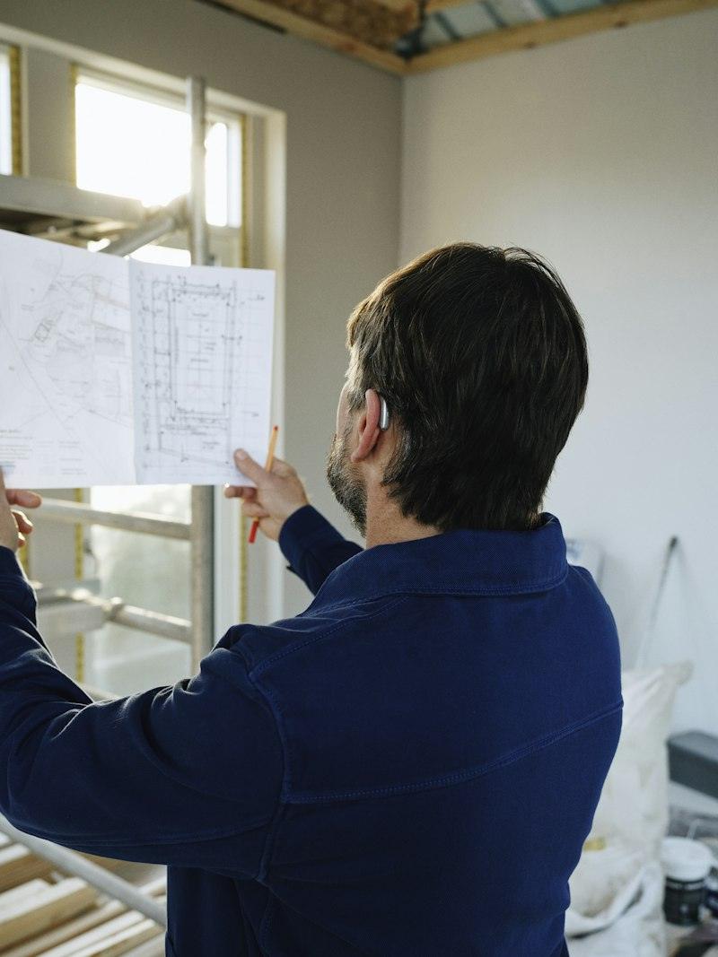Professional revisant plànols a l'obra