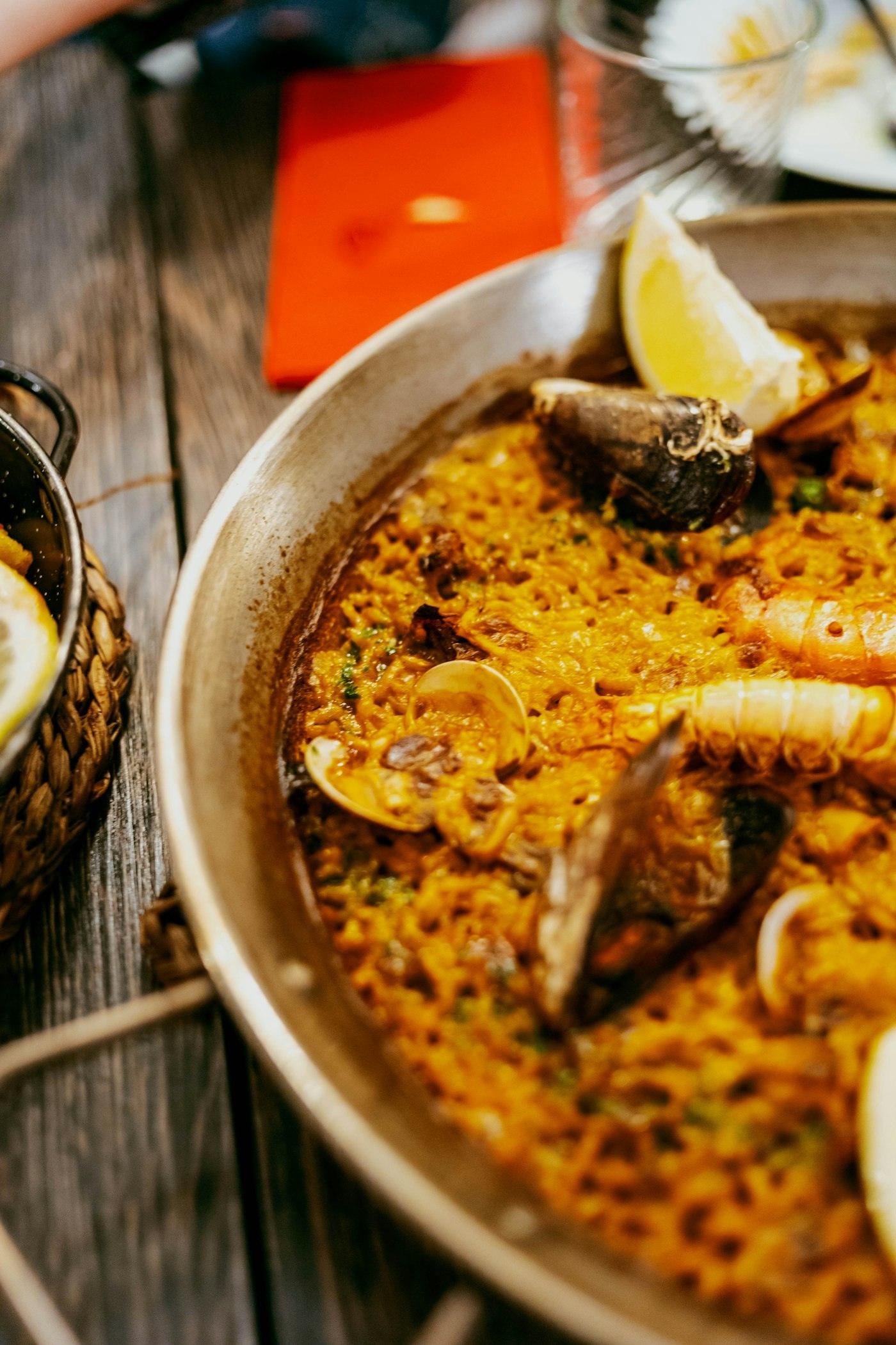 Paella d'arròs de marisc amb llimona sobre una taula de fusta