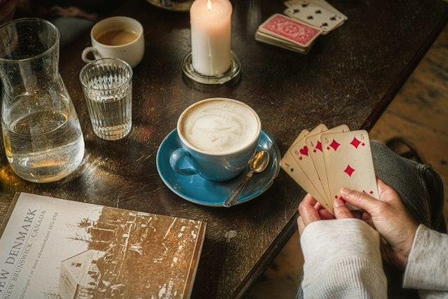 Cafè, espelma i cartes sobre una taula de fusta